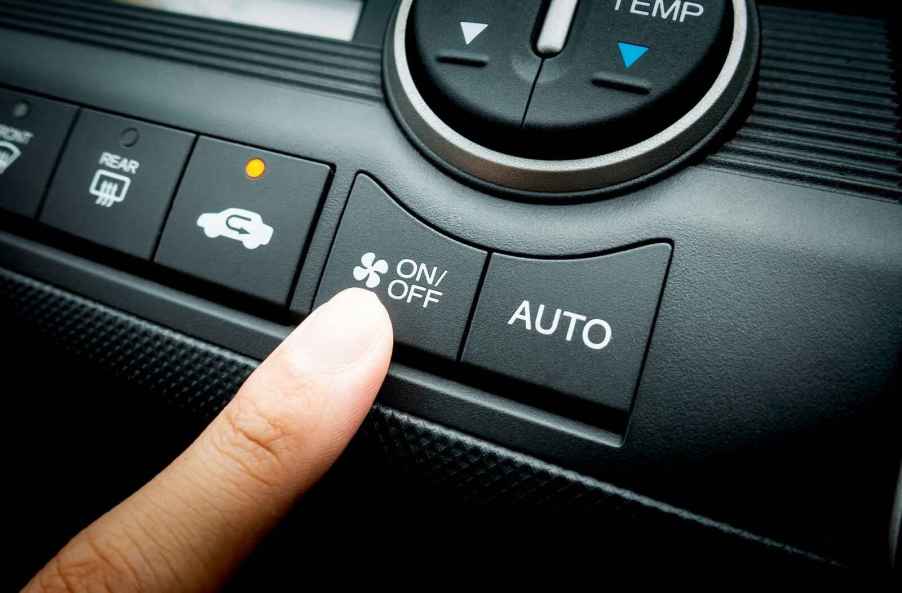 A finger getting ready to push AC on/off button in car with recirculate button on