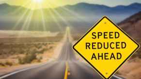 "Speed limit reduced ahead" sign with blurred wavy road in background