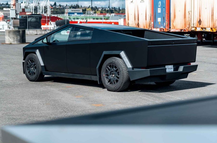 A Tesla Cybertruck parked at left rear angle color appears almost black due to lighting