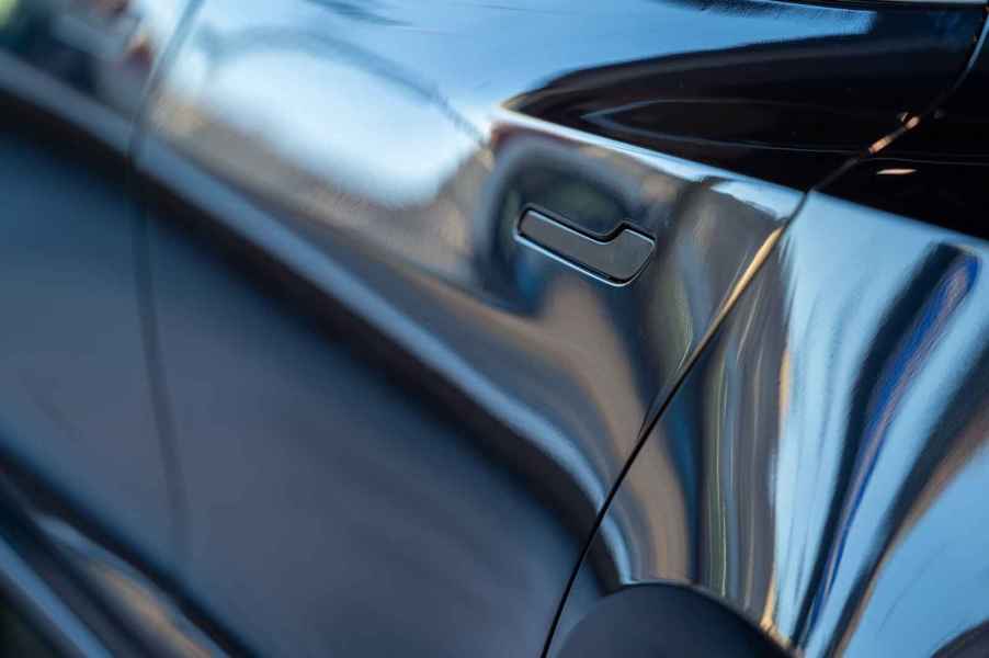 A close view of the left rear door handle on a Tesla EV