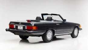 A vintage Mercedes-Benz SL convertible parked in right rear angle view on white floor and background