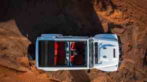 White Jeep Wrangler Rubicon with its convertible top down, parked in the desert.