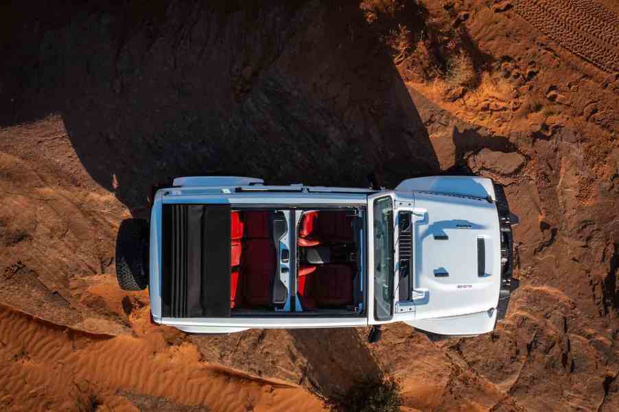 White Jeep Wrangler Rubicon with its convertible top down, parked in the desert.