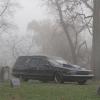 A hearse in a foggy cemetery