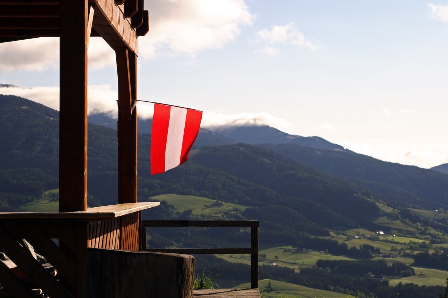 Austrian flag hanging from the porch of a lodge in the Alps mountain range