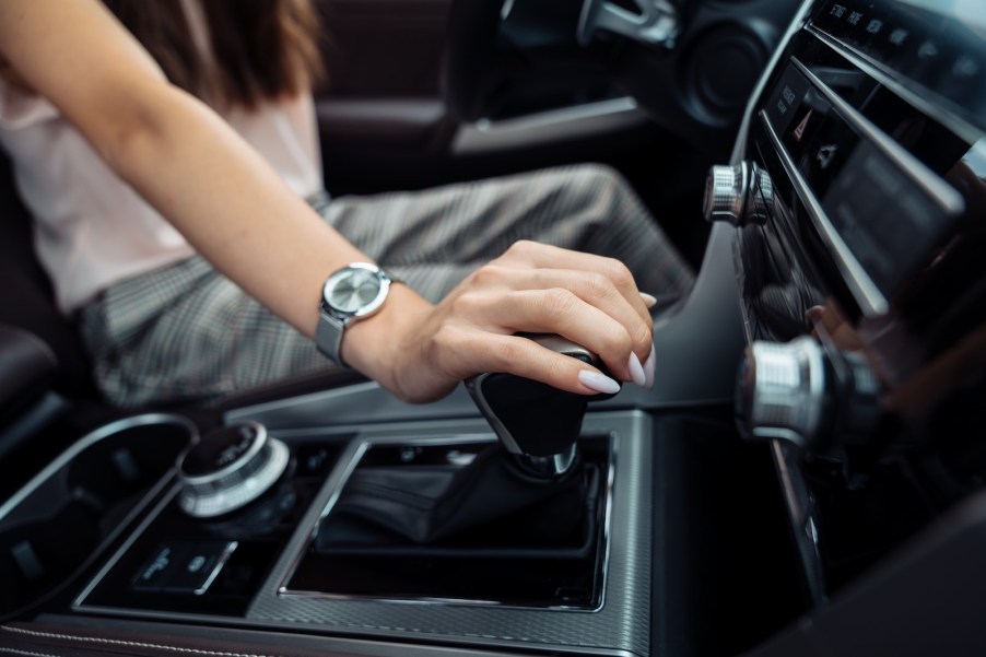 A driver puts her hand on the lever of an automatic transmission