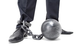 Man in nice pants and shoes drags along a ball-and-chain