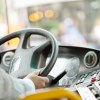 The hands of a driver on the steering wheel of a city bus.