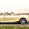 Woman drives a yellow Cadillac convertible concept EV down a country road.