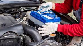 A technician replaces a car battery in an older vehicle.