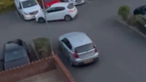 A bad driver in a white hatchback hits cars in a parking lot.