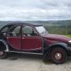 Red and black Citroen 2CV parked on a mountaintop.