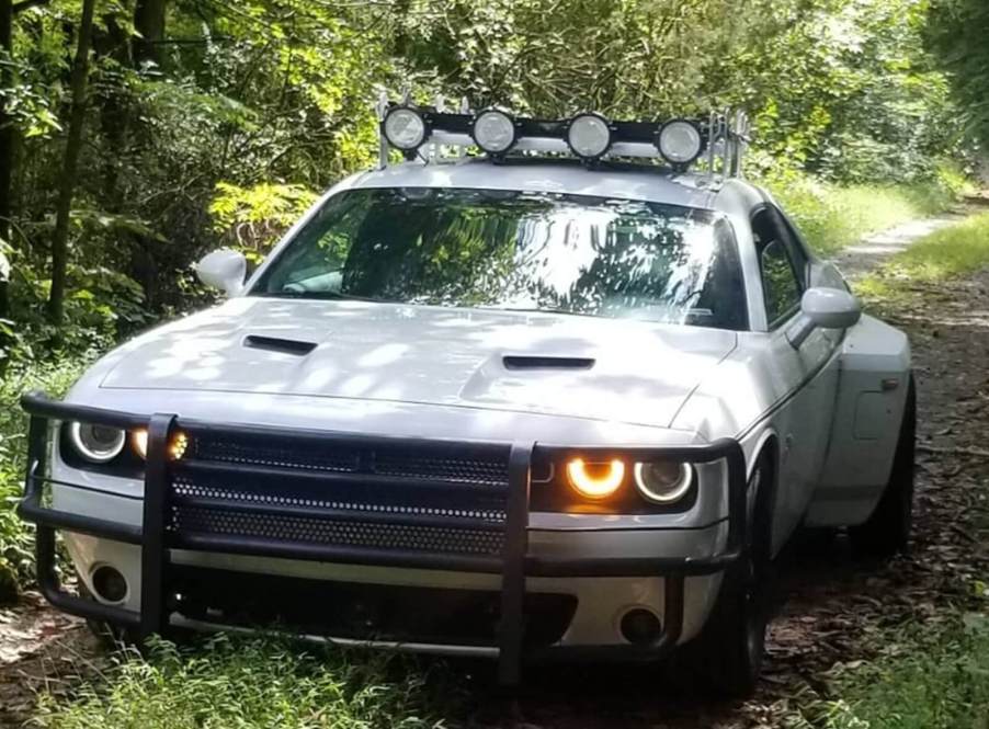 A custom Dodge Challenger Widebody dually build off-road on a trail with a light rack and push bar.