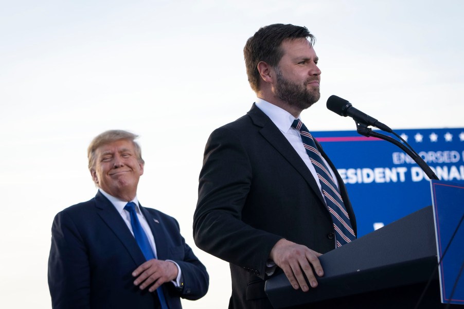 Senator J.D. Vance stands at a podium in Ohio while Presidential candidate Donald Trump smiles behind him