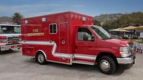 An ambulance driver prepares to drive a bright-red fire department ambulance.