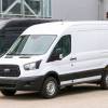 White Ford panel van parked in a lot with other work vans.