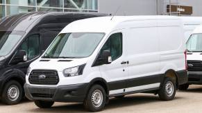 White Ford panel van parked in a lot with other work vans.