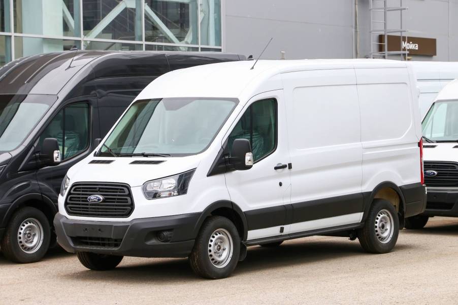 White Ford panel van parked in a lot with other work vans.