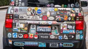 A Honda Element covered in decals like an honor roll bumper sticker and an Amoeba Records decal.