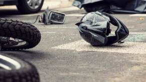 A motorcycle rider and their helmet at the scene of a crash.