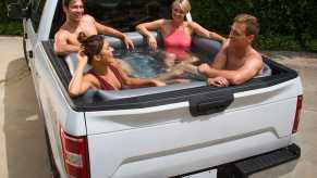 Four people relax in a truck bed filled with water to make a pool.