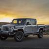 A gray Jeep Gladiator parks on a pad at sunrise.