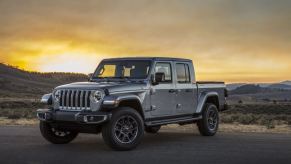 A gray Jeep Gladiator parks on a pad at sunrise.