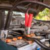 A car owner jumps a battery with a set of jumper cables.