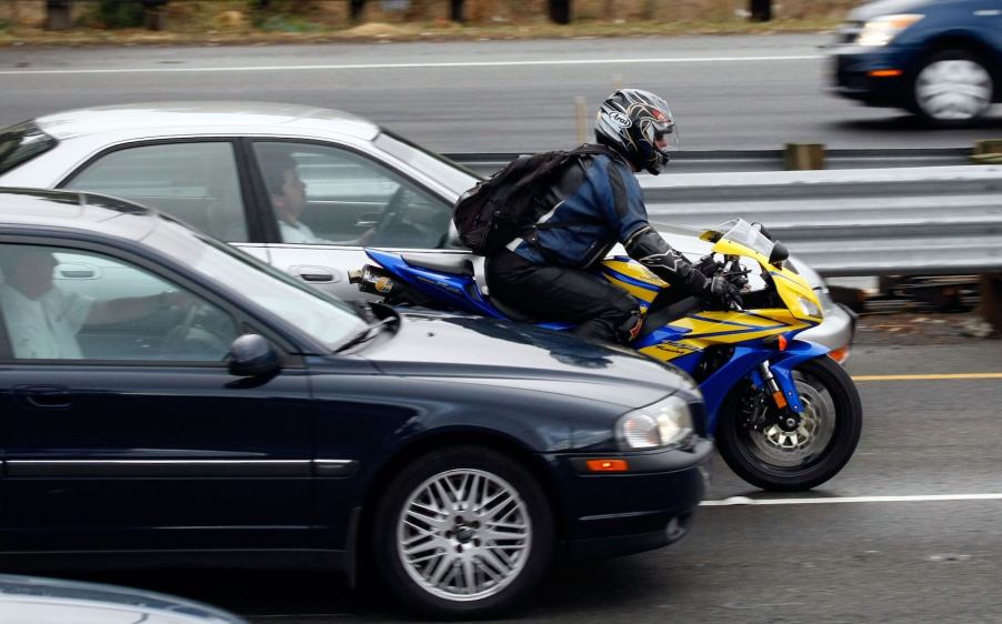 A motorcycle riding between fast-moving highway traffic as he splits lanes in California