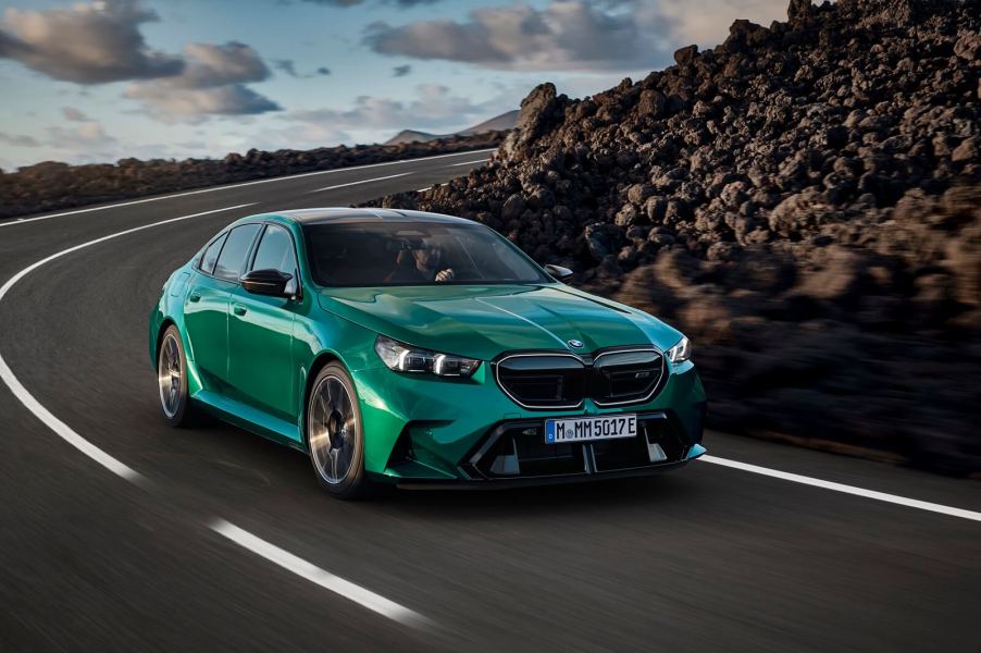 A green 2025 BMW M5 drives around a corner.