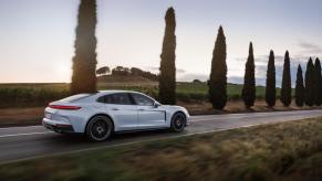 A white 2025 Porsche Panamera E-Hybrid on a country road.