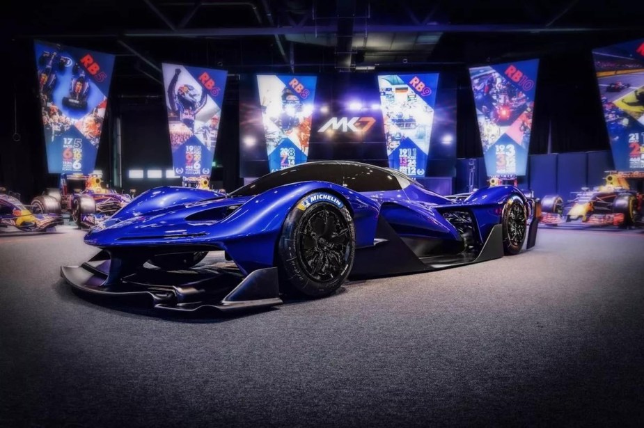 Blue hypercar by Red Bull parked on an autoshow stage.