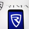 The Rimac logo on a cellphone in front of a Rimac sign.