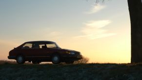 A Saab 900 Turbo shows off its merit among sports cars at sunset.