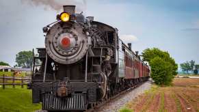 Restored classic steam locomotive on train tracks in the country.