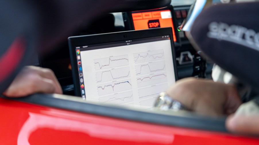 A technician looks over the screen readout in the cockpit of an autonomous Toyota Supra race car