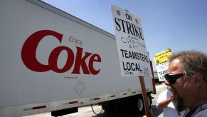 Teamster truck drivers strike outside a coca cola bottling plant, a semi truck driving past