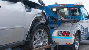 A tow truck takes a vehicle to a police impound lot.