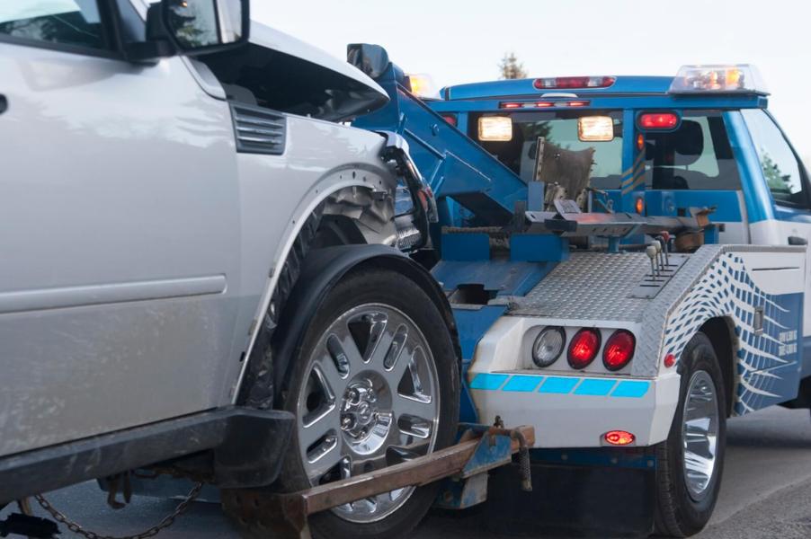 A tow truck takes a vehicle to a police impound lot.