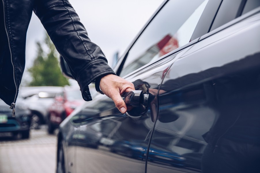 A man's hand on a car door handle opening it as a car theft example using the "Game Boy" key emulator theft device