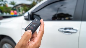 A person unlocking a white car with a key fob