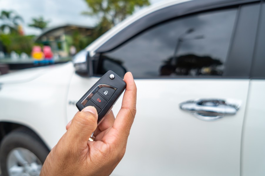 A person unlocking a white car with a key fob