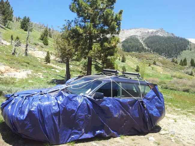 An SUV covered in tarp to protect it from marmots this is recommended by the National Park Service