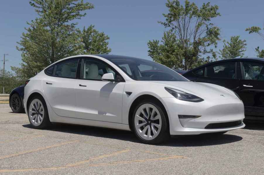 A white Tesla Model 3 sedan parked in a lot in right front angle view