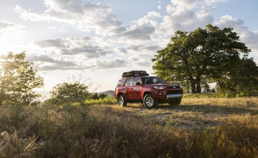 A red 2017 Toyota 4Runner TRD driving off-road in a grassy area at dusk this year model is known as one of the best Toyota 4Runner years