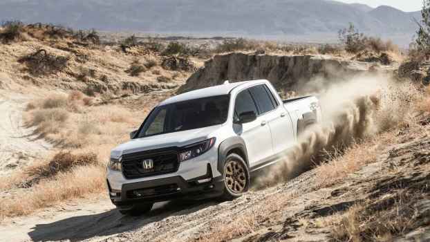 A white 2021 Honda Ridgeline Sport driving on a rough, scrubby, dry desert trail