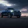 A blue 2022 Toyota Tundra parked in right front angle view with headlights on in darkening outdoors