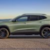 A green 2024 Chevrolet Trax parked in full left profile view in front of water