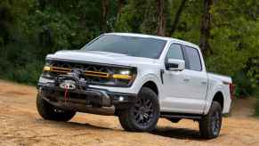 A white 2024 Ford F-150 Tremor with SecuriCode door entry keypad parked on incline in left angle view on uneven dirt