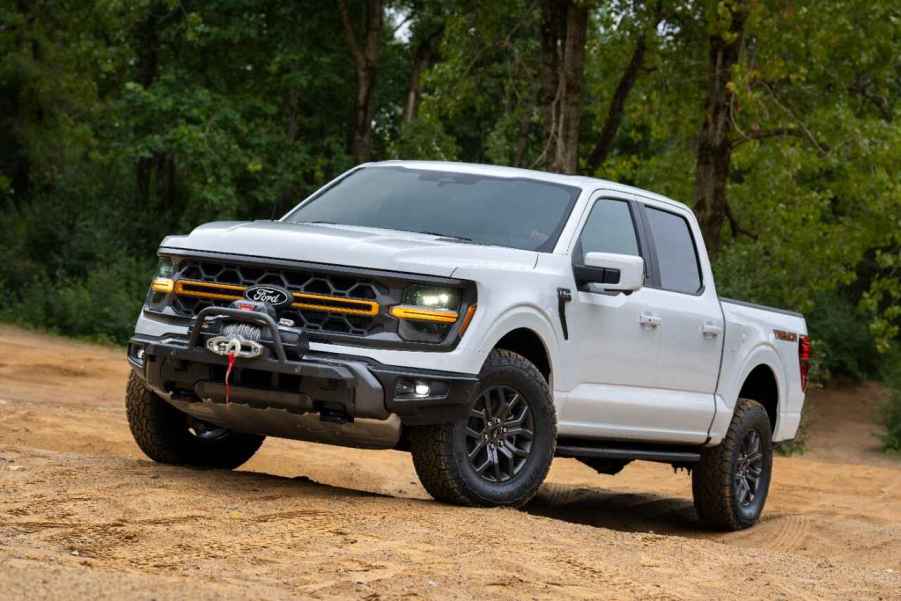 A white 2024 Ford F-150 Tremor with SecuriCode door entry keypad parked on incline in left angle view on uneven dirt